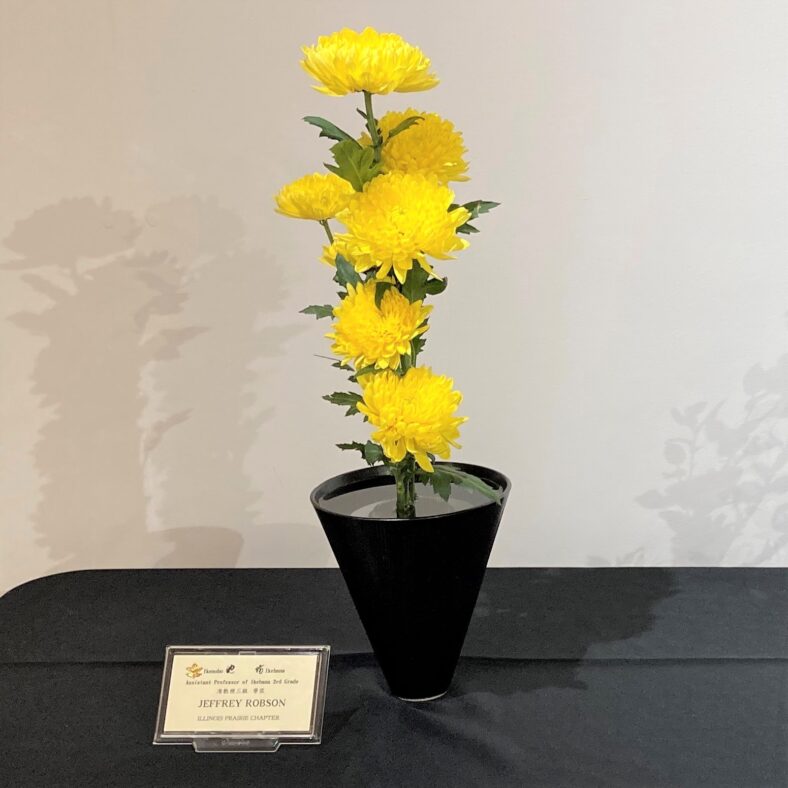 An exquisite floral display arranged in a black bowl on a table, crafted by the Ikenobo School of Ikebana.