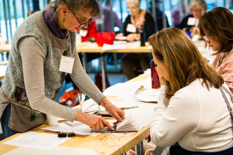 Instructor Judilee Fitzhugh on the left assists a student in a textile workshop