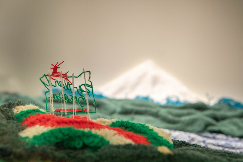 Behind view depiction of the Portland White Stag Sign with mount hood in the background on a structure of fabric