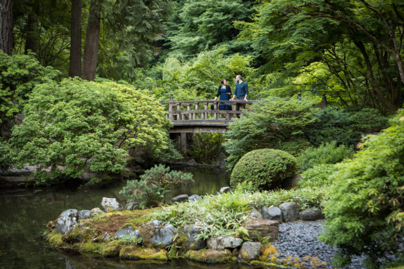 Two people standing on a bridge overlooking a pond in Portland Japanese Garden.