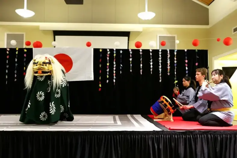 Shishimai traditional Japanese lion dance and a group of people dressed in japanese costumes performing on stage