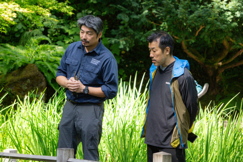 Hugo Torii speaks with an artist named Takahiro Iwasaki in the Strolling Pond Garden of Portland Japanese Garden.