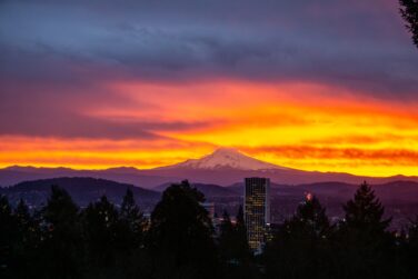 Sunrise over Mt. Hood, ribbons of pink, yellow, red, and purple highlight the sky.