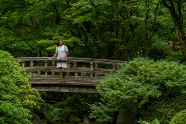 A female student standing on a wooden bridge in the Portland Japanese Garden